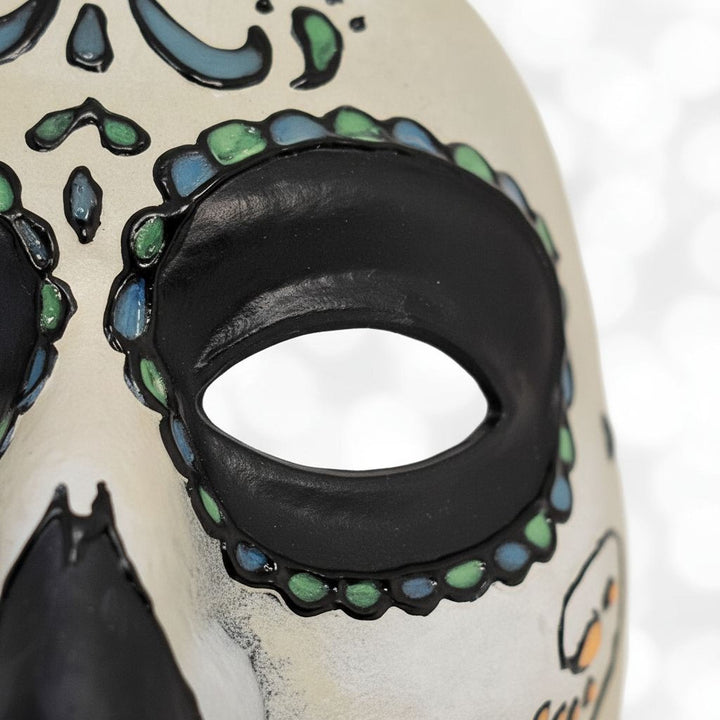 A close-up view of a colorful Day of the Dead-inspired mask with intricate designs and patterns.